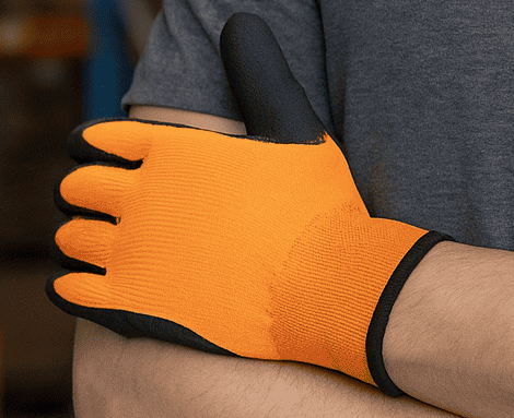 Warehouse worker wearing orange safety gloves in a modern warehouse aisle with racking, symbolizing best work gloves for warehouse safety